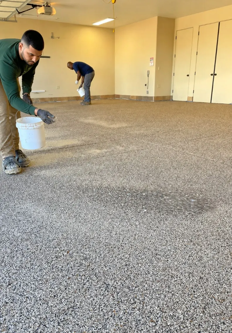 Installers broadcasting decorative material across a garage floor
