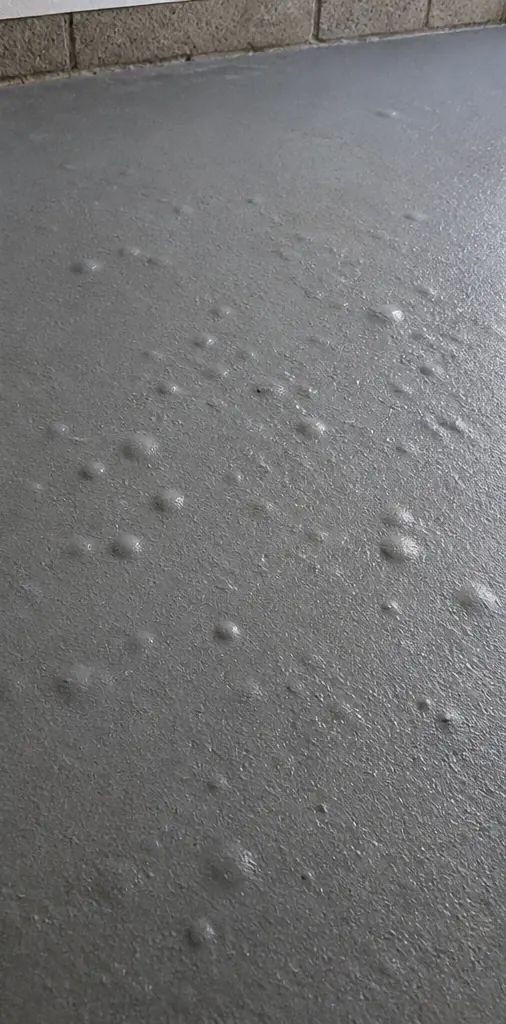 Bubbles and blisters raised across a garage floor coating