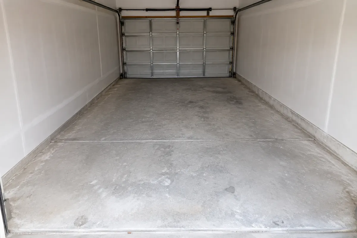 Empty one-car garage with a dusty unfinished concrete slab